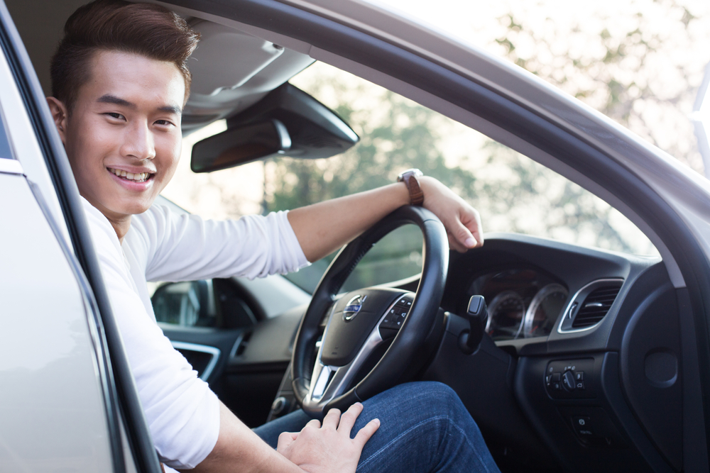 ผู้ชายนั่งอยู่บนรถ หาคำตอบว่ารถอายุ 10 ปีทําประกันชั้น 1 ได้ไหม